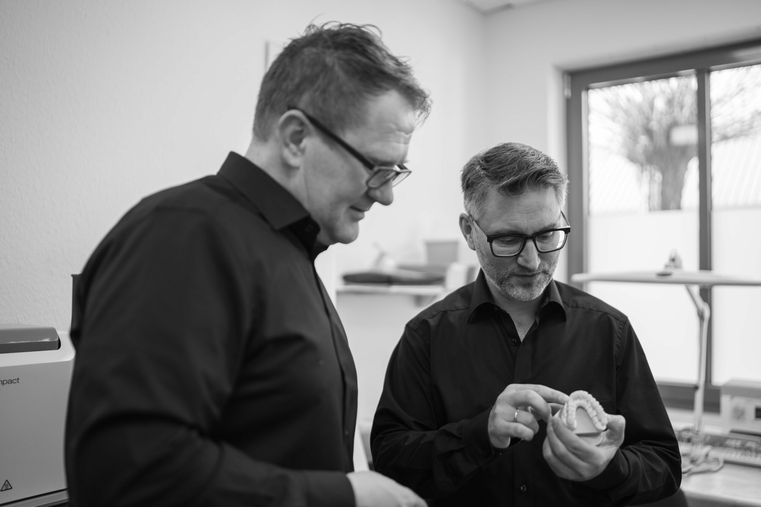Waldemar Pahl und Claus Fischer, beide Zahntechnikermeister, begutachten eine zahntechnische Arbeit
